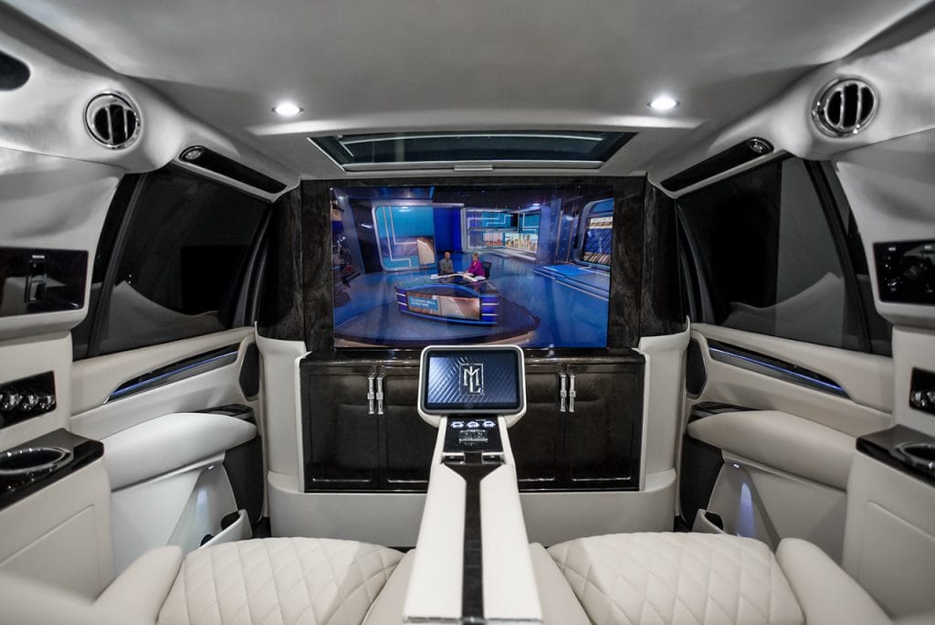 Luxury vehicle cabin with TV partition, bar area and entertainment system